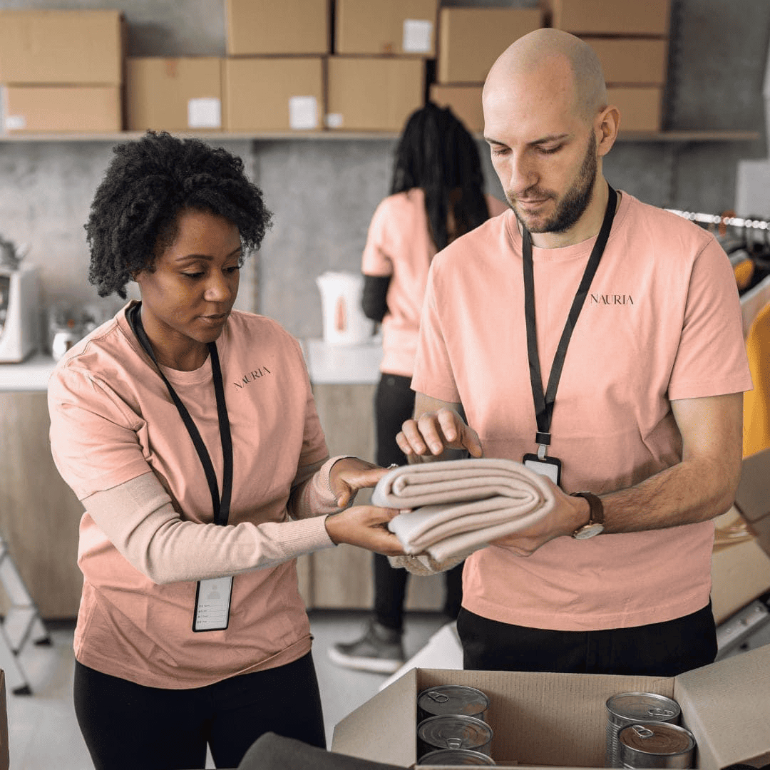 Zwei Mitarbeiter bereiten Nauria Retouren für Hilfsorganisationen vor. Nachhaltigkeit und soziales Engagement in Aktion.